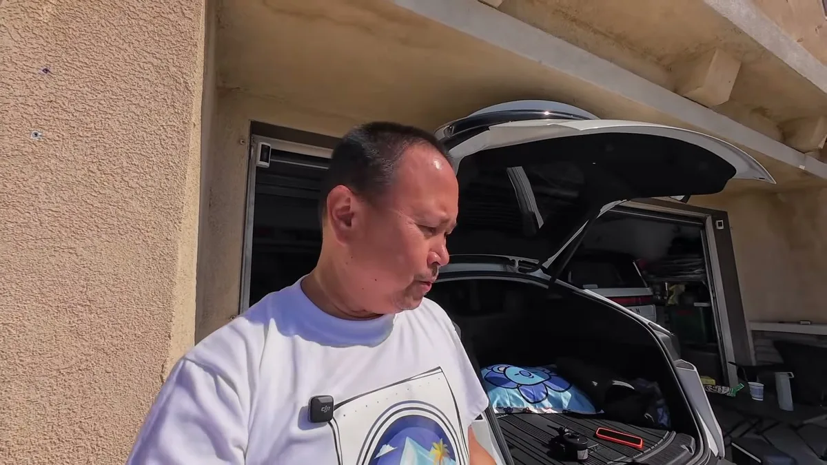 Man looking into Model Y trunk observing air mattress setup