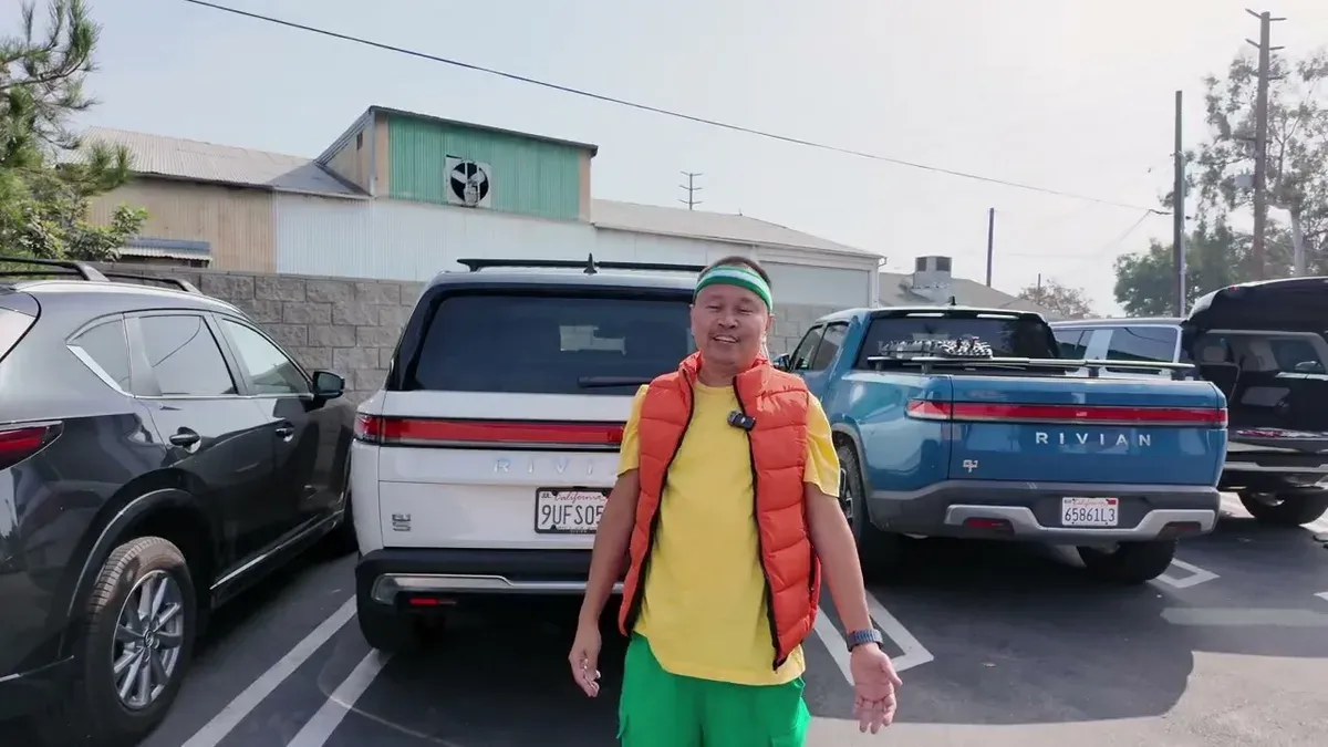 Sherwin in an orange vest standing between a white R1S and a blue R1T in the Campsite Brewing lot