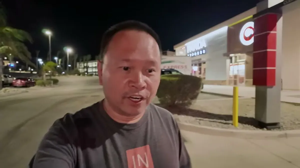 Man speaking in parking lot at night near brightly lit store
