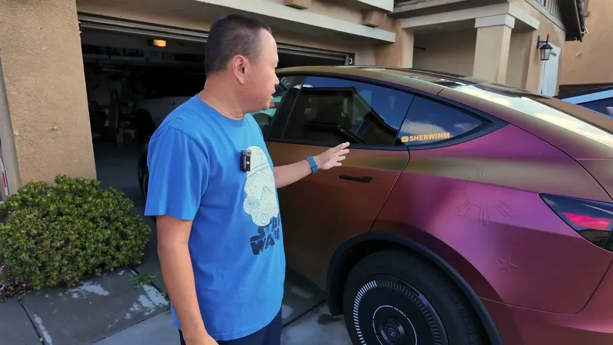 Man pointing at the rear passenger door of the custom wrapped gold and bronze Tesla Model Y Juniper, showing the door issue.