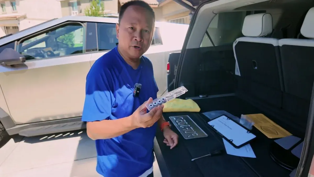 Man holding license plate screws next to open Rivian R1S trunk, Cybertruck visible in background.
