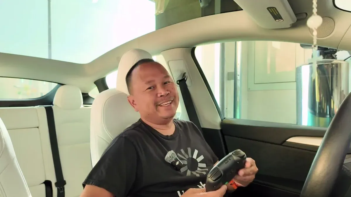 Sherwin in the Model Y Performance smiling and holding a Jowua gaming controller