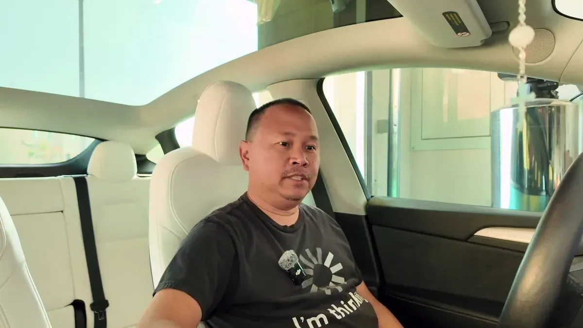 Sherwin in the Model Y Performance driver seat with white interior, talking to camera