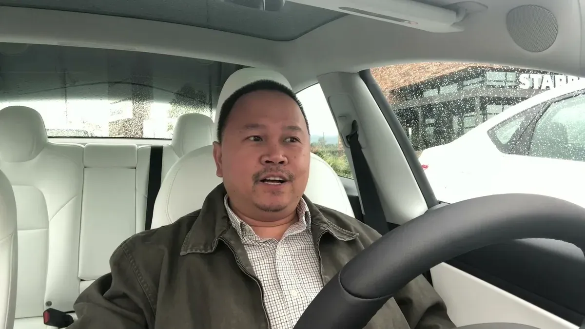 Sherwin sitting in the Model 3 driver's seat outside Starbucks in the rain
