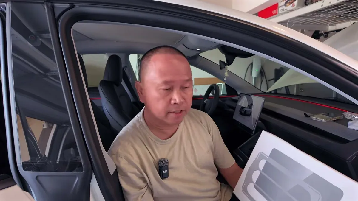 Man in Tesla driver's seat holding a Jowua 9H tempered glass screen protector box