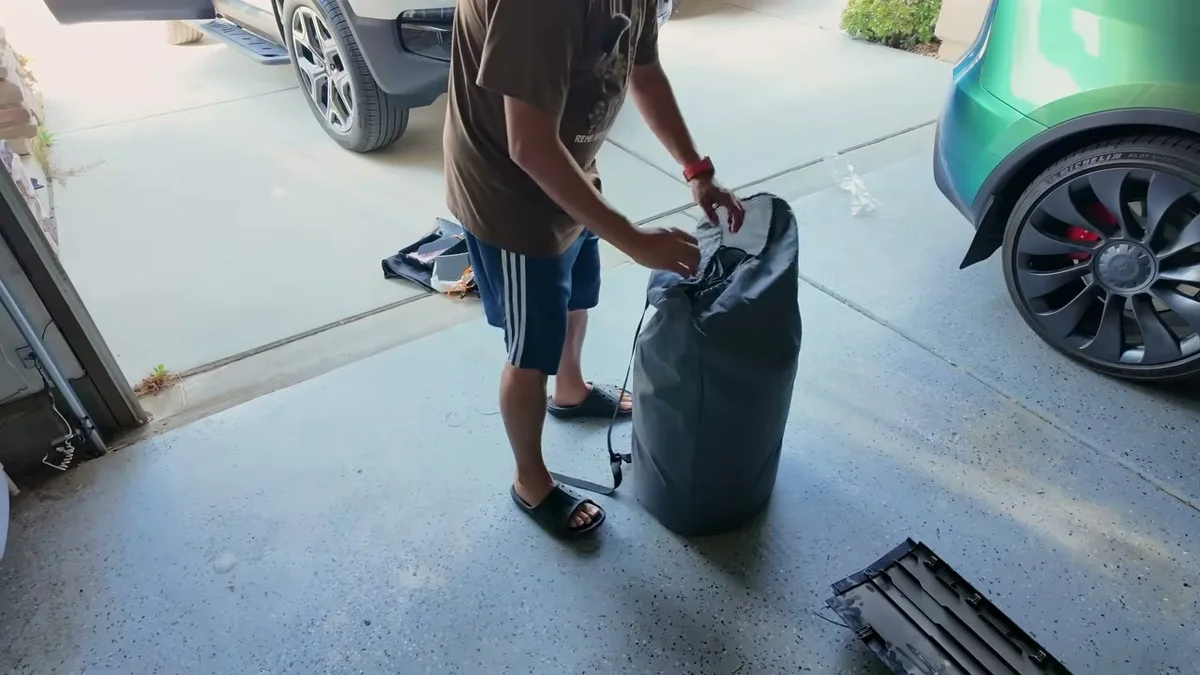 Sherwin pulling the EVBase air mattress out of its storage bag in the garage