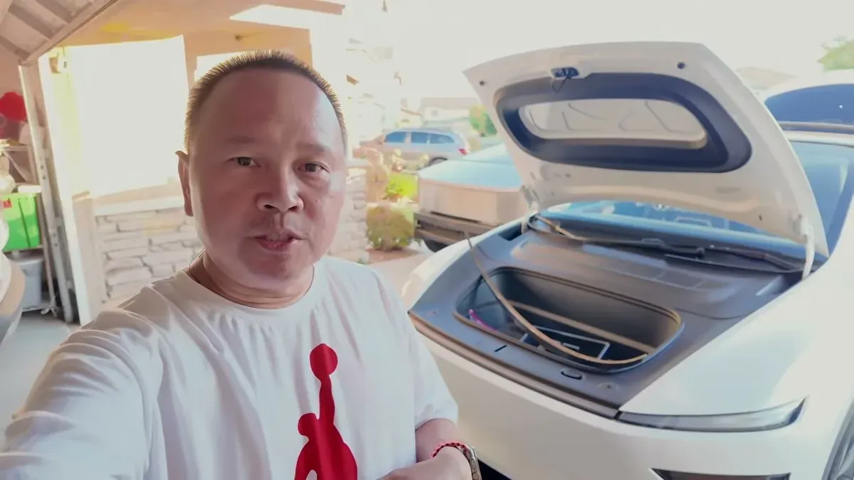 Sherwin standing in his garage in front of a white Model Y Juniper with the frunk open