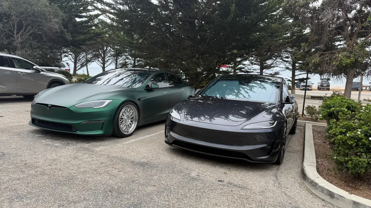 A matte green Tesla Model S and a Model 3 parked along the coast on Pacific Coast Highway