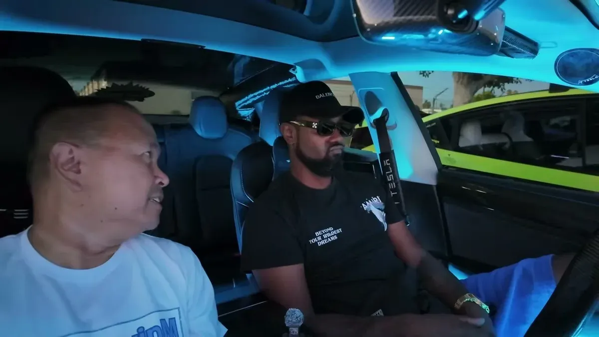 Reese and Sherwin inside the Model 3 with green ambient lighting during the dream car discussion