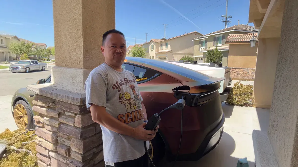Sherwin standing next to his wrapped Model Y Juniper with the Mobile Connector plugged in, the Cybertruck parked behind it