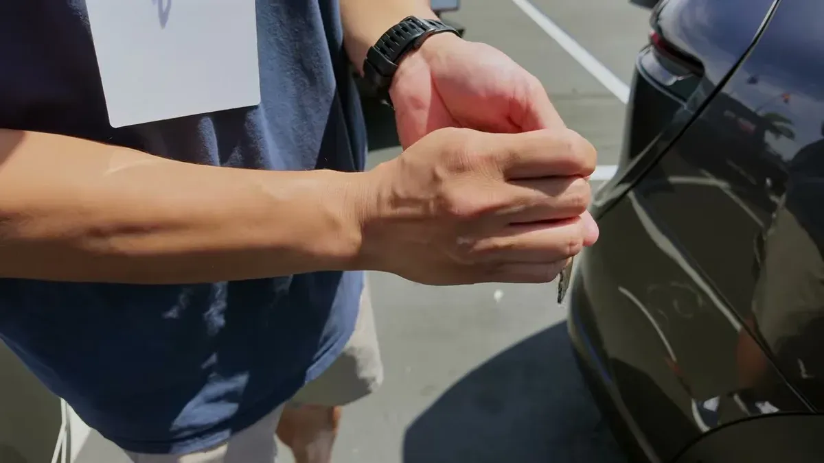 Hands holding the Lucid Gravity key fob next to the vehicle exterior.
