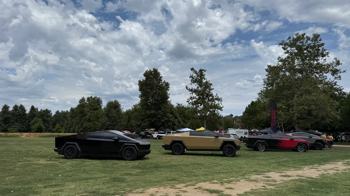 Three Tesla Cybertrucks in black, tan, and red parked in a row at the Bates Nut Farm EV event