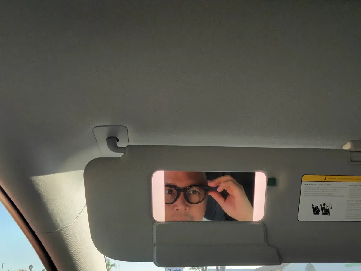 Sherwin reflected in the Model Y visor mirror wearing Meta Glasses Oakley HSTN
