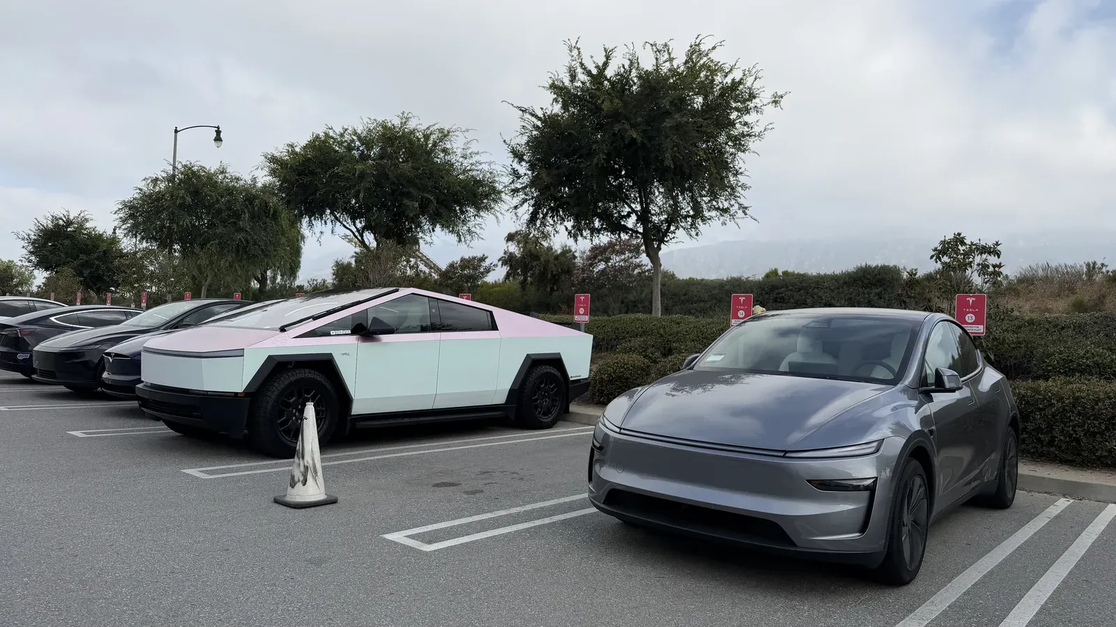A pink-wrapped Cybertruck parked next to a silver Tesla Model Y in a SoCal lot.