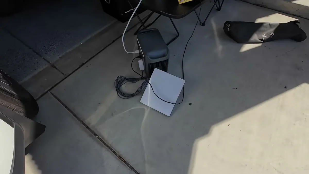 Overhead view of Anker power station, laptop, and charging cables on concrete next to camping setup