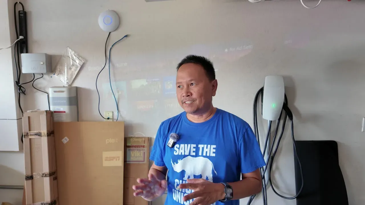 A projector powered by the inverter throwing a Roku home screen onto the garage wall behind Sherwin.
