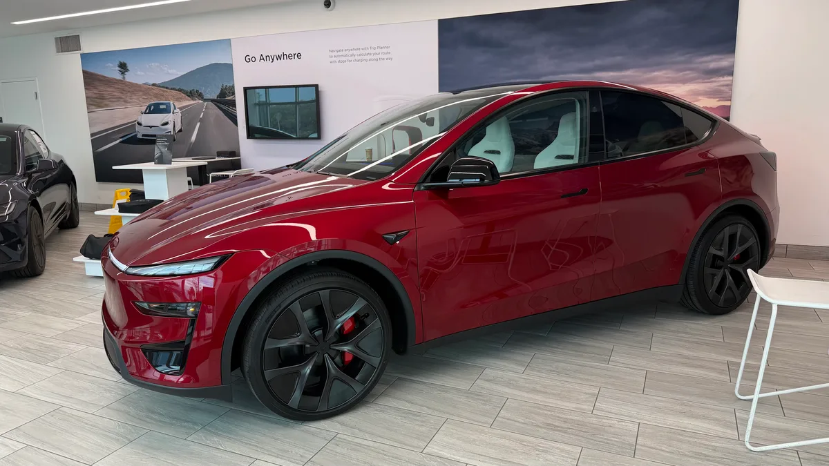 2026 Tesla Model Y Juniper Performance in Ultra Red, three-quarter side view in a Tesla showroom