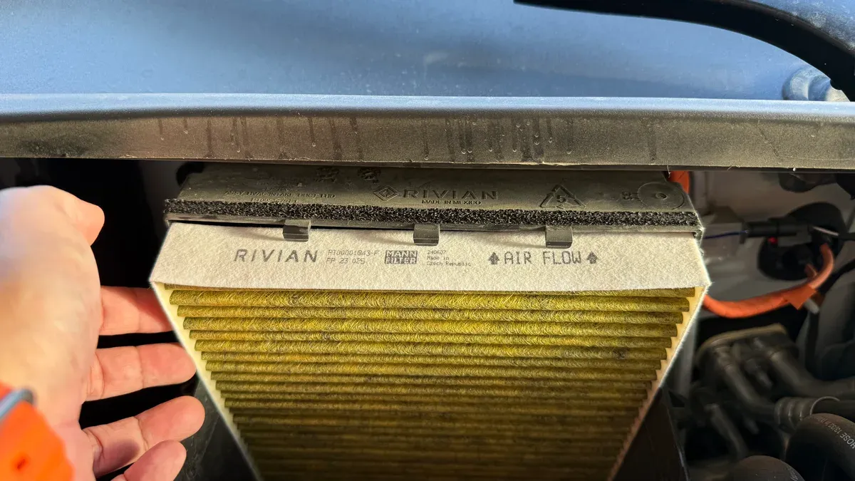 Hand removing yellow MANN FILTER cabin air filter from Rivian R1S frunk