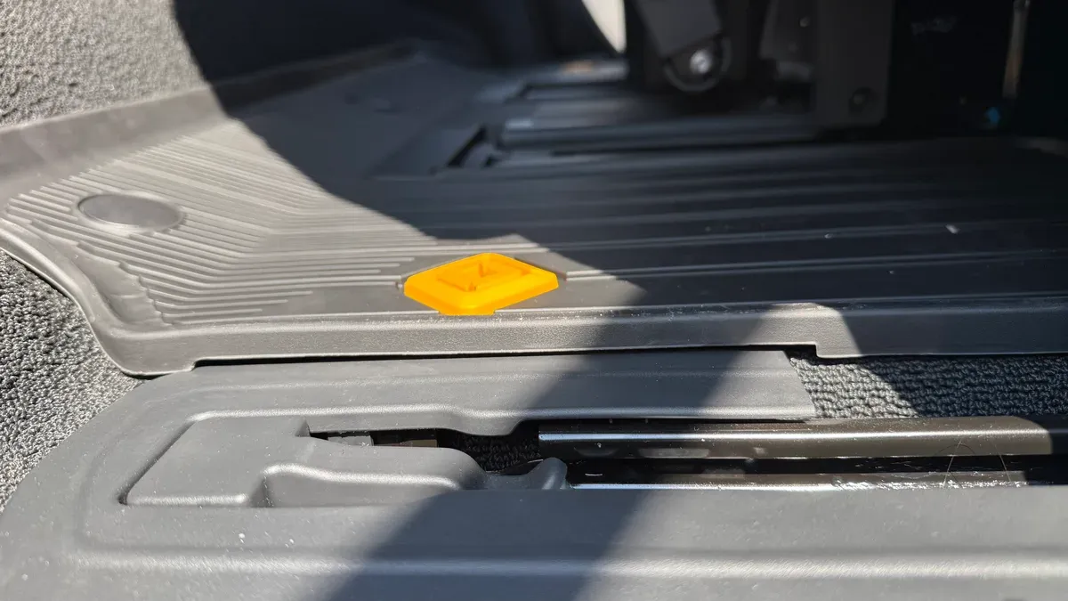Low-angle view of Rivian all-weather mat installed on passenger side showing seat rail and mat edge