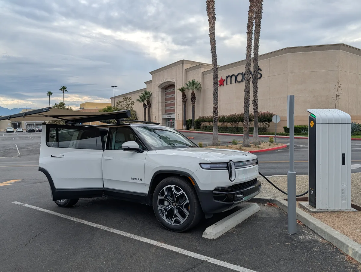 White Rivian R1S with awning deployed while charging in front of Macy's