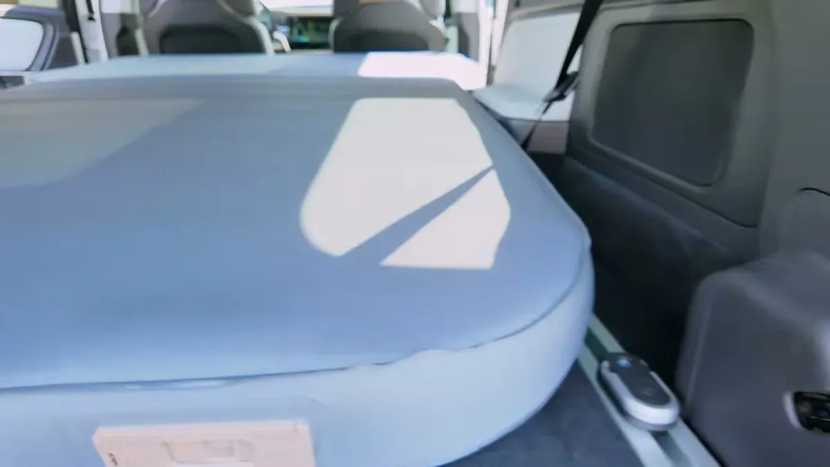 Close-up of the light blue EVBase inflatable mattress perfectly fitted in the Rivian R1S cargo area, with outlet access visible on the sides