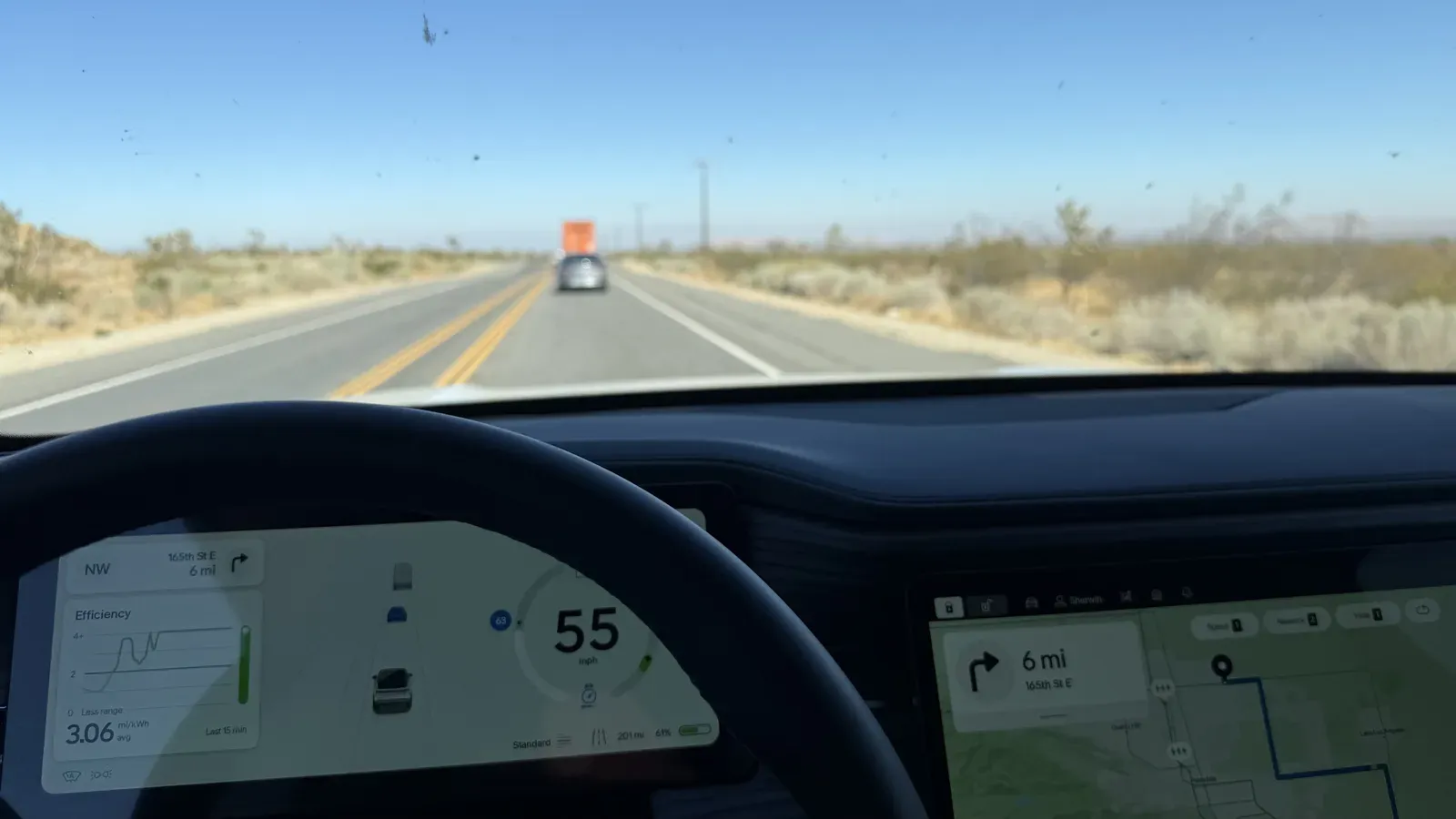 Rivian R1S driver display on a two lane desert highway running adaptive cruise control at 55 mph
