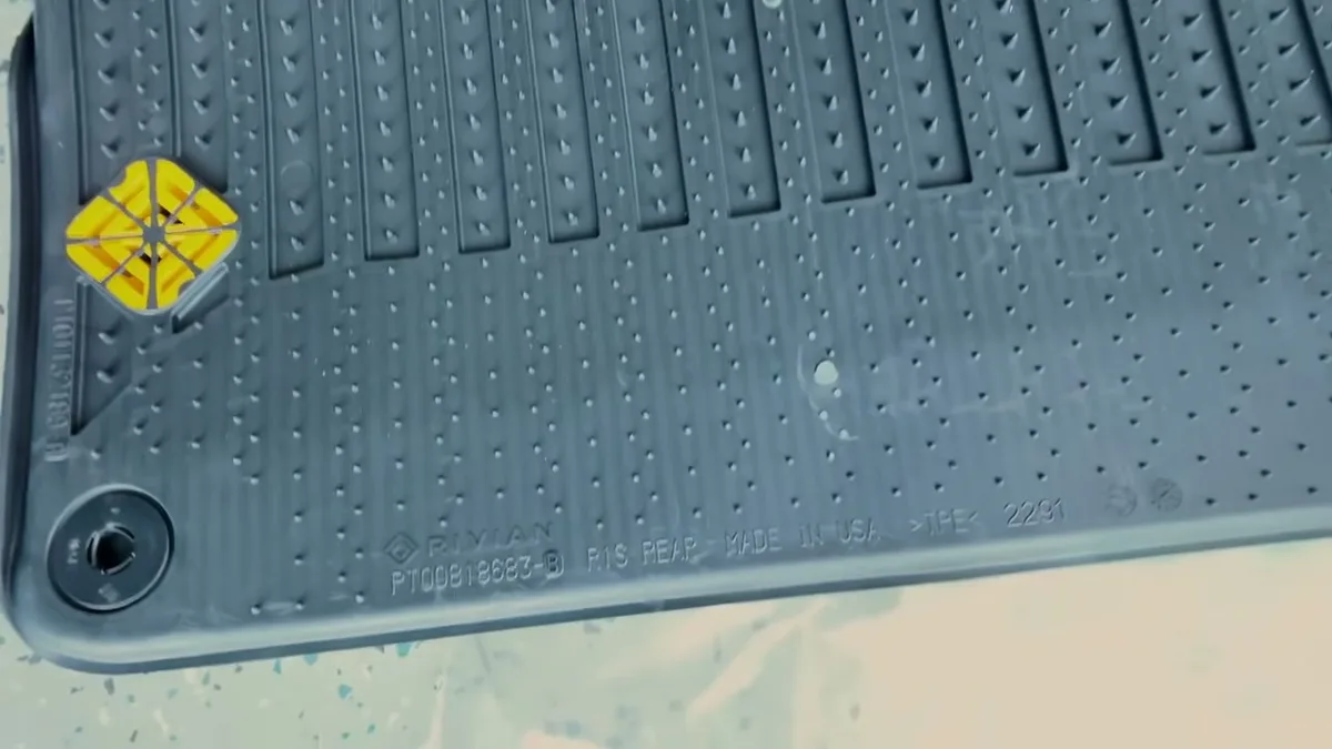 Close-up of Rivian R1S rear floor mat label showing yellow logo and embossed Made in USA text