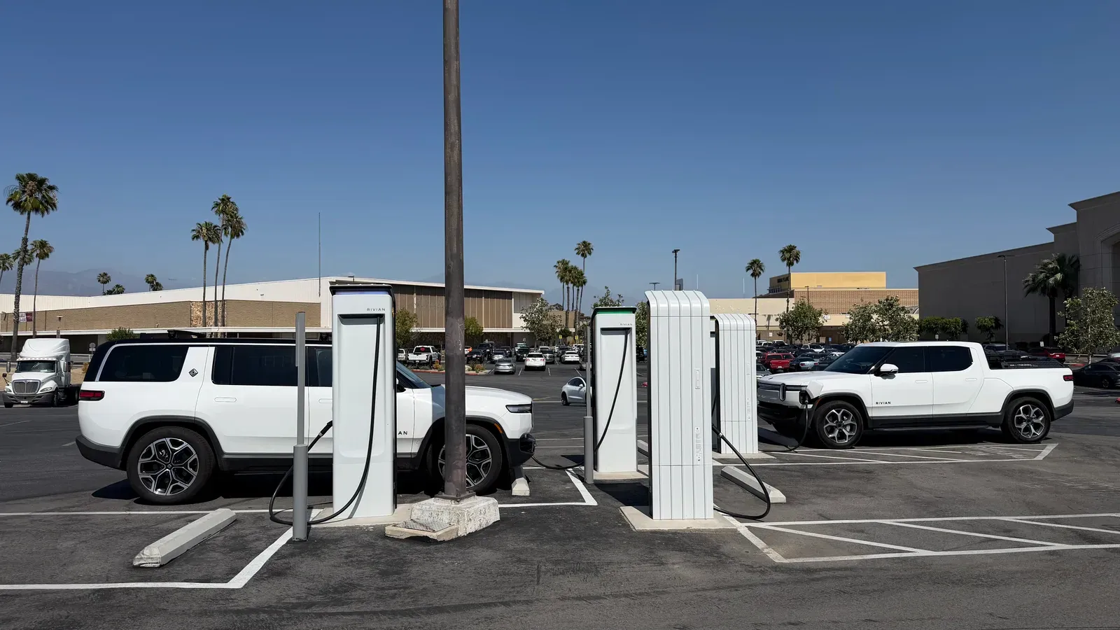Two Rivian R1S and R1T charging at a Rivian Adventure Network station under the SoCal sun