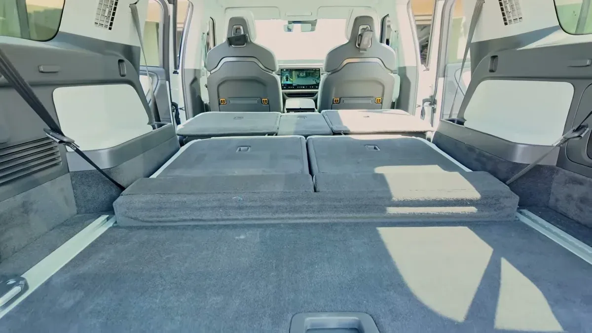 Interior of a white Rivian R1S with second and third-row seats folded completely flat for car camping