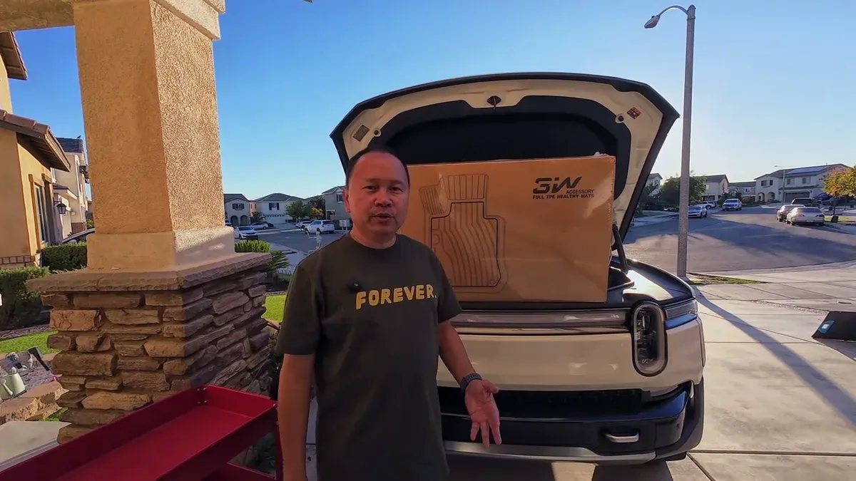 Man in green shirt standing in front of white Rivian R1S with frunk open, revealing 3W floor mat box