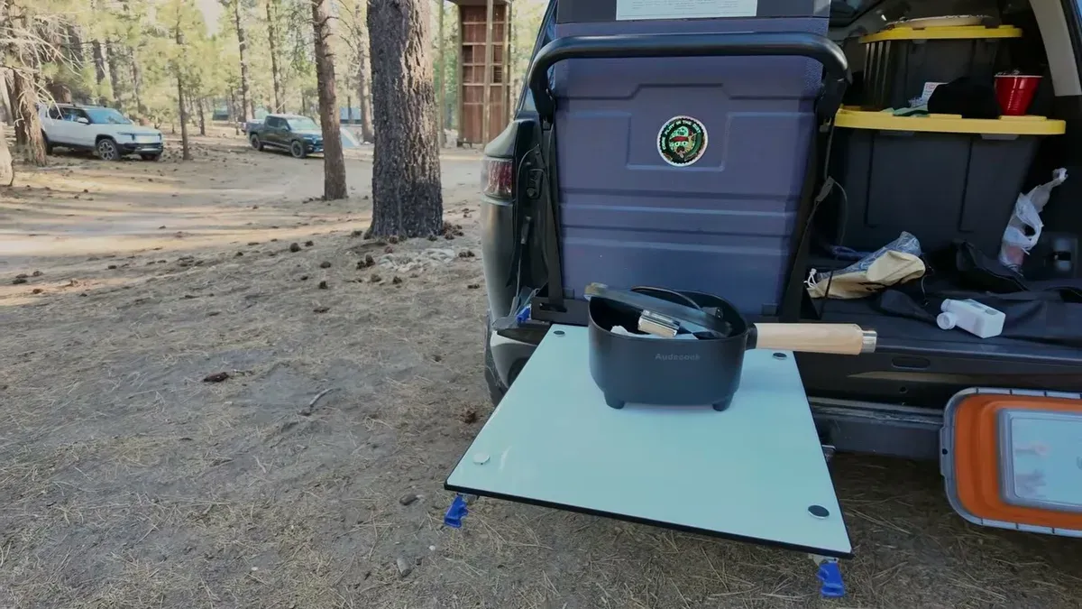Rivian R1S open tailgate with slide-out table, portable stove, and organized camping gear at Toyo Trail Pass