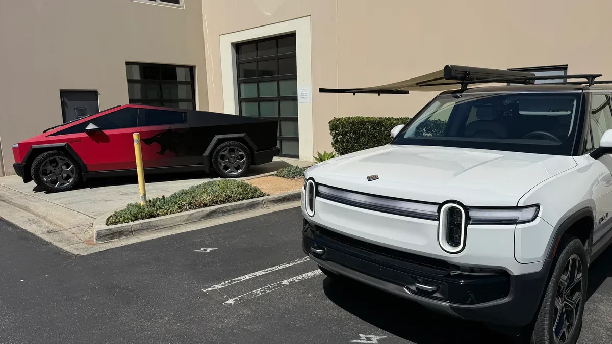 White Rivian R1S parked in front of custom red and black Tesla Cybertruck with wolf wrap