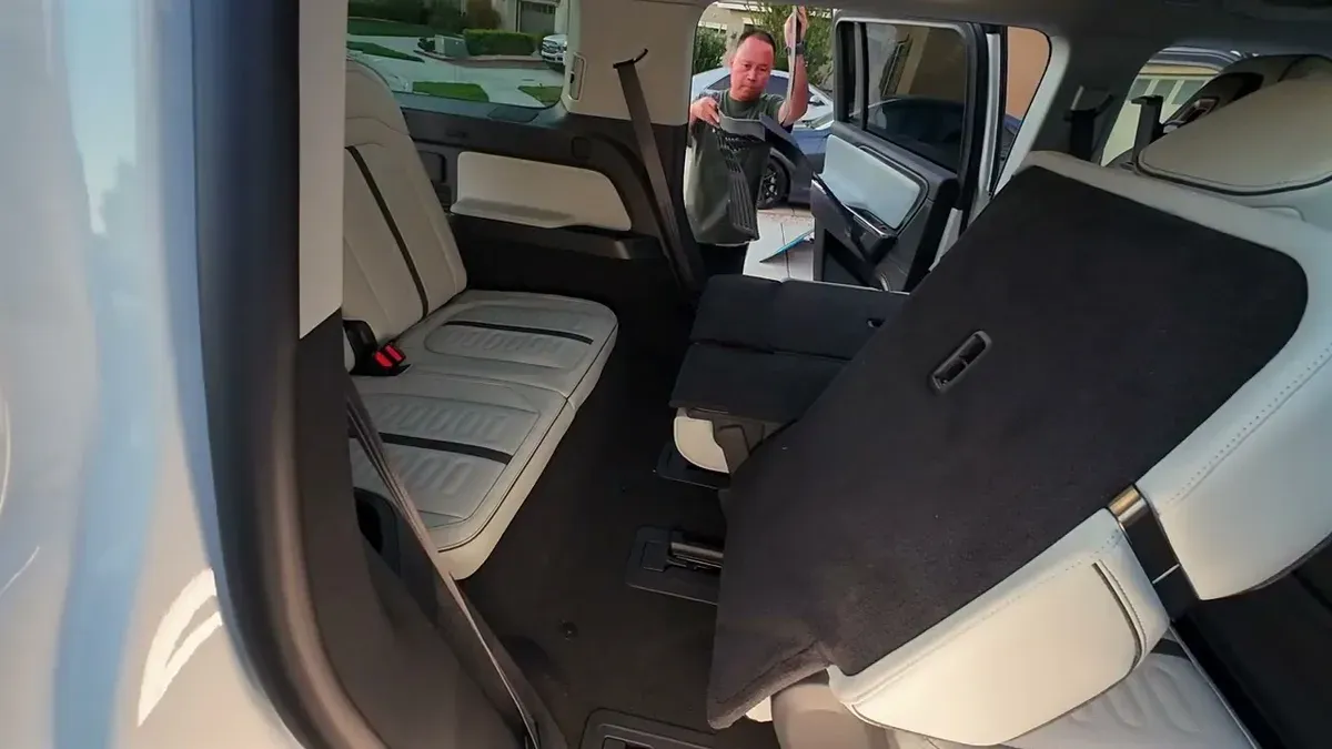 Man installing 3W third-row floor mat inside Rivian R1S with third-row seats folded