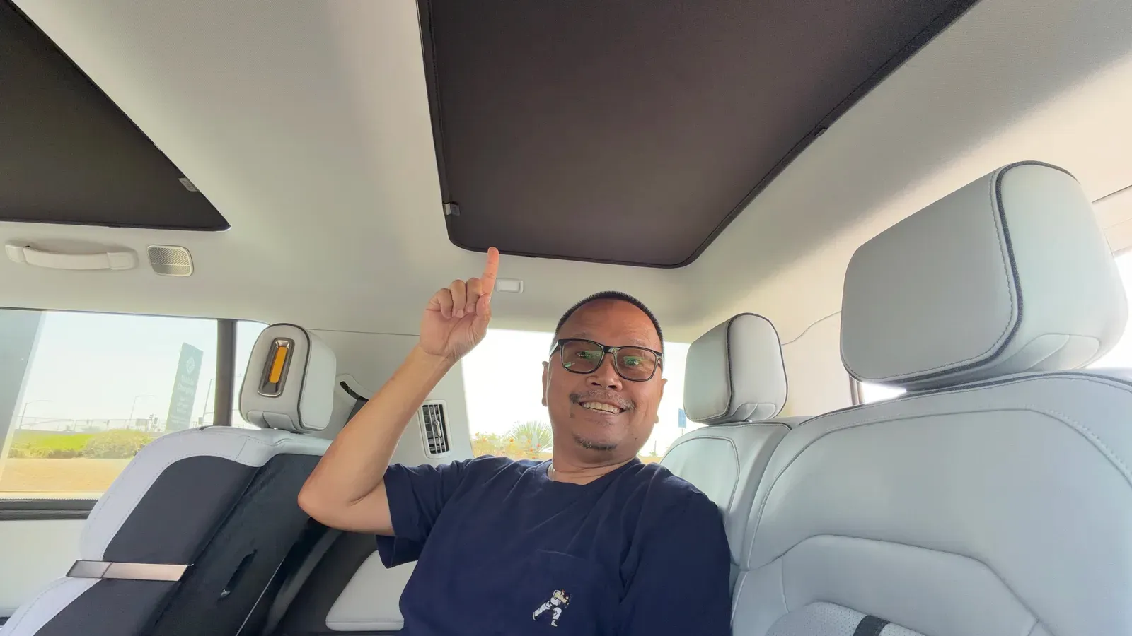 Sherwin in the Rivian R1S third row pointing up at the installed Vion roof shade