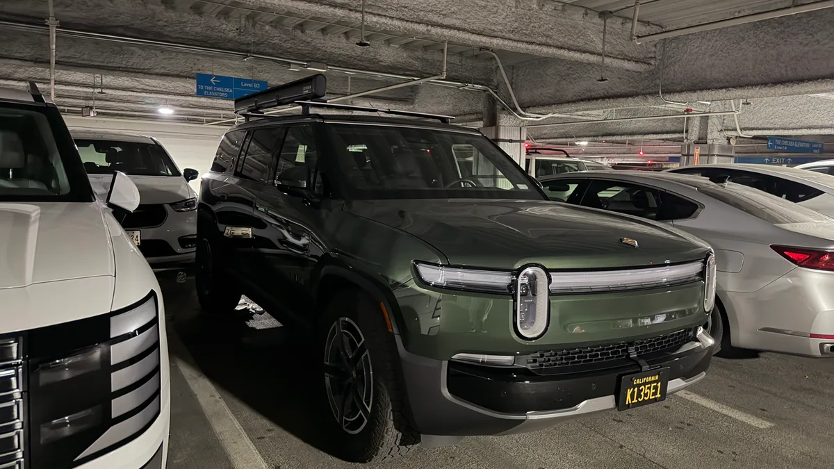 Dark green Rivian R1S with roof rack in underground parking garage.
