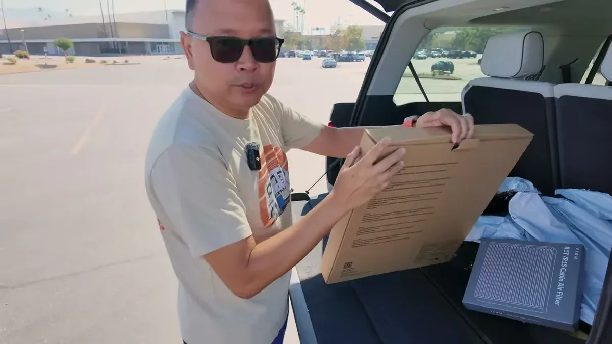Holding Vion roof shade and cabin air filter boxes next to open R1S trunk
