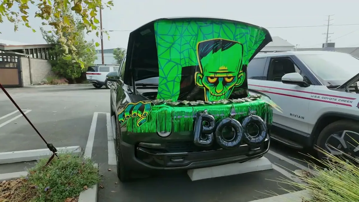 Dark green Rivian R1T with Frankenstein graphic and BOO balloons on the tailgate