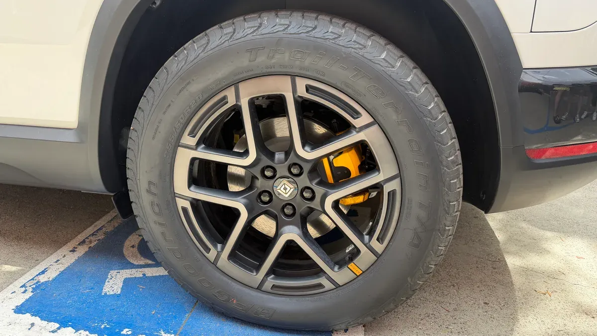 Close-up of Rivian R2 wheel with black multi-spoke rim, BFGoodrich tire, and yellow brake caliper.