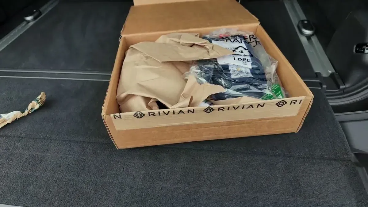 Open Rivian-branded box in trunk containing referral merchandise items