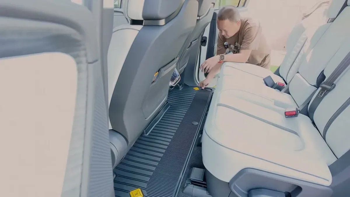 Man installing Rivian all-weather mat in the second row of a white R1S