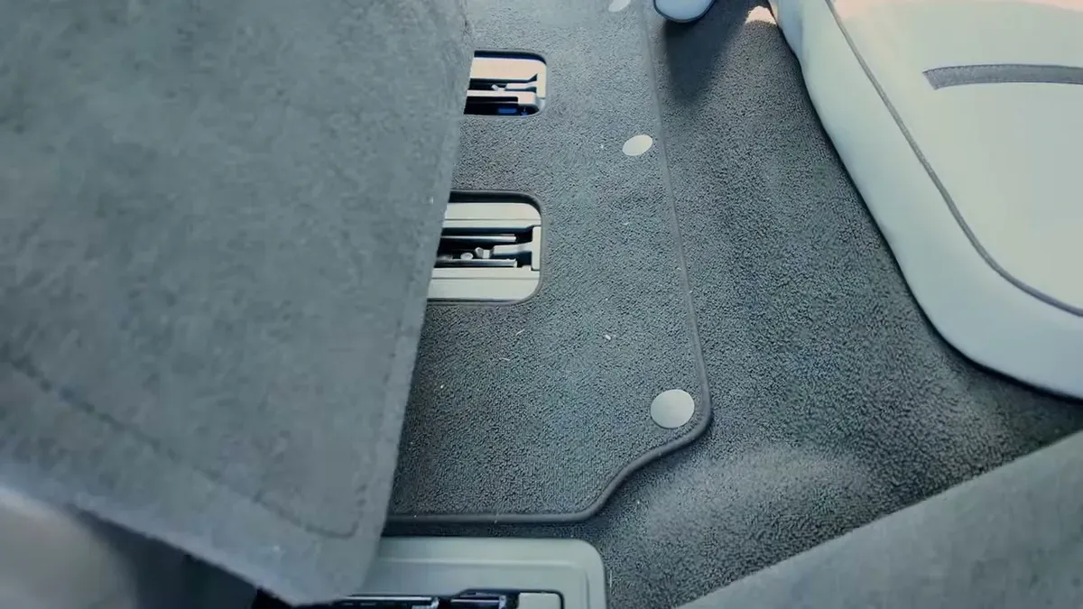 Gray carpeted third-row floor in Rivian R1S showing factory anchor points before mat installation