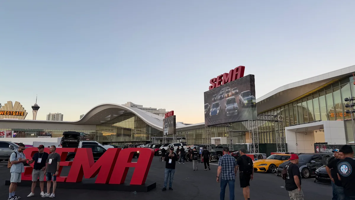 SEMA 2025 entrance at dusk with the large red SEMA letters, display screen, and Westgate Las Vegas in the background