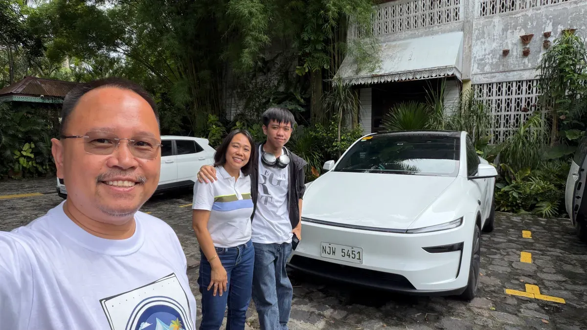 Sherwin, Joy, and her son Noah standing next to Joy's white Tesla Model Y in the Philippines