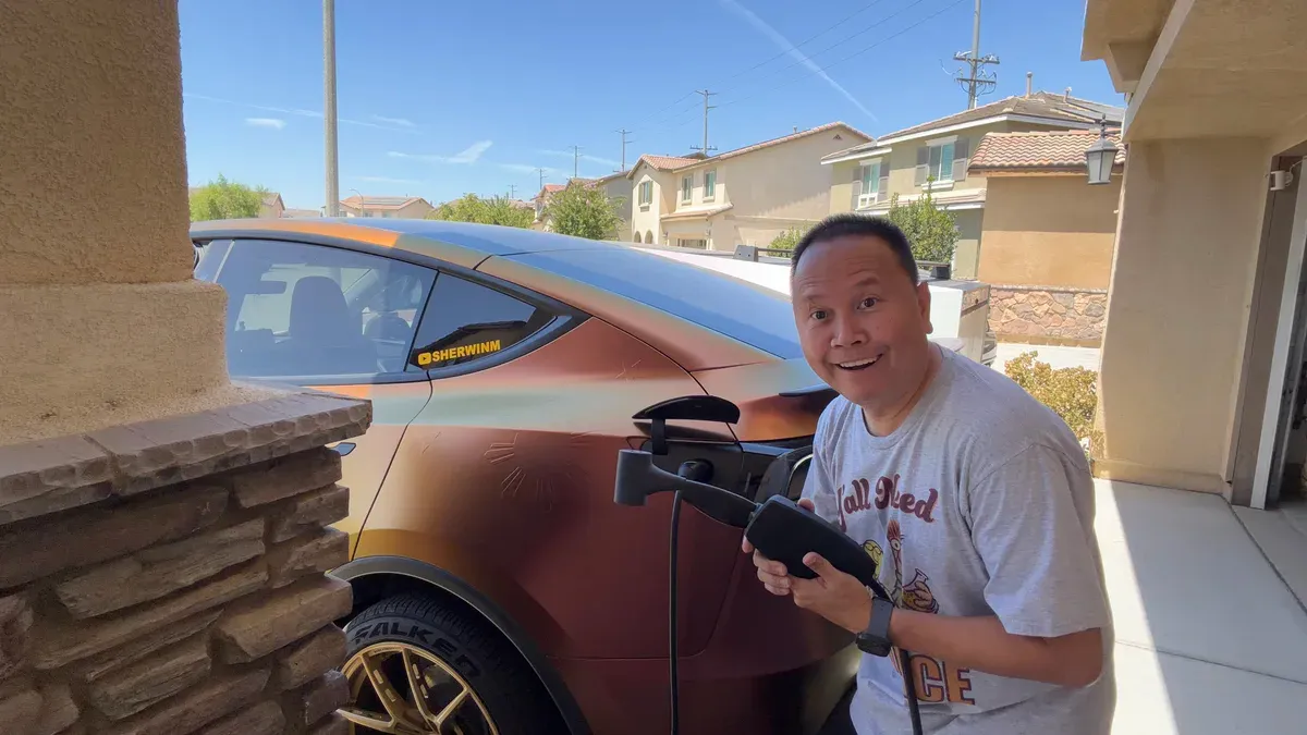 Sherwin smiling next to the Model Y with the Tesla Outlet Adapter in hand