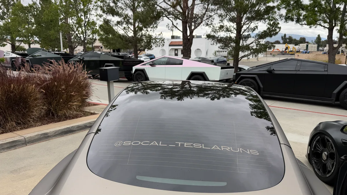 Rear window with SOCAL_TESLARUNS decal and Cybertrucks in the background.