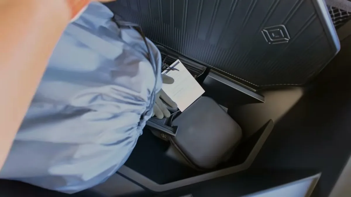 Hand placing the EVBase air mattress bag into the frunk of a white Rivian R1S