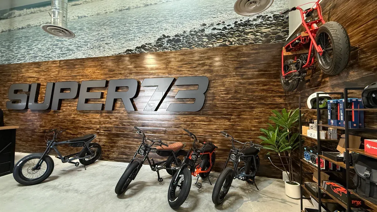 Interior of Super73 showroom with electric bikes displayed on floor, SUPER73 logo on wooden wall