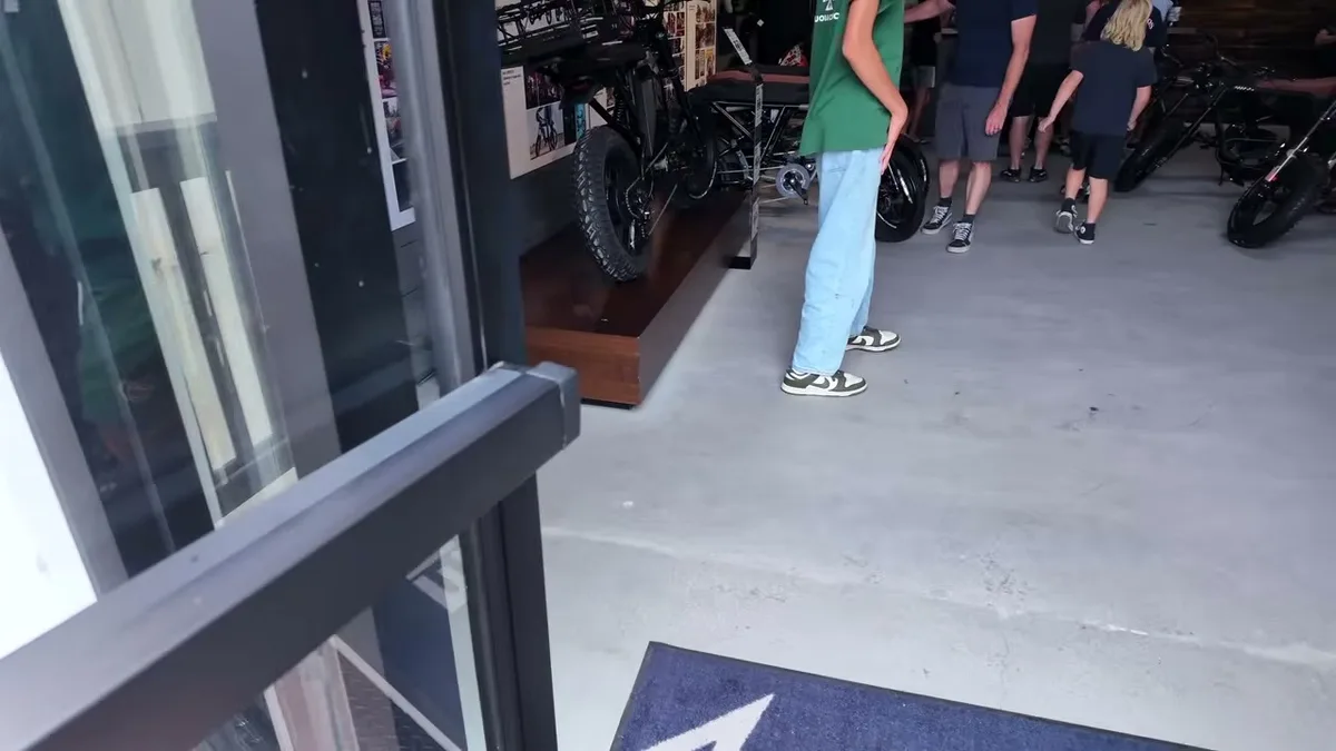 People viewing custom electric bikes on display inside a modern showroom with concrete floors.