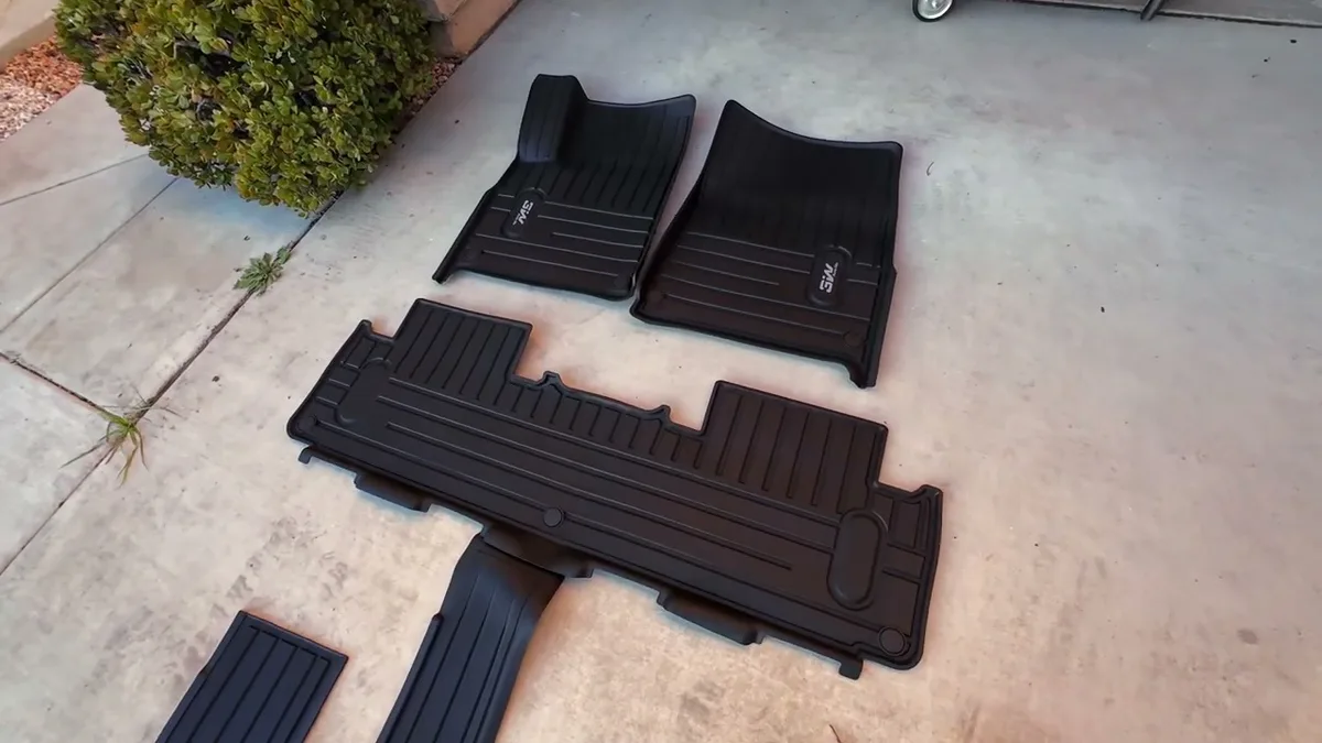 Black 3W floor mats for Rivian R1S laid out on concrete driveway showing texture and design