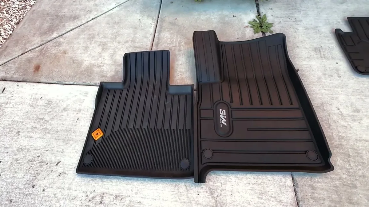 3W floor mat next to Rivian OEM mat side by side on concrete for direct comparison